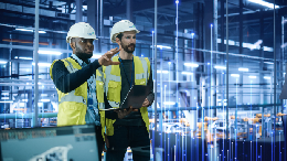 People in hard hats in front of HVAC equipment, reviewing diagnostics on tablet